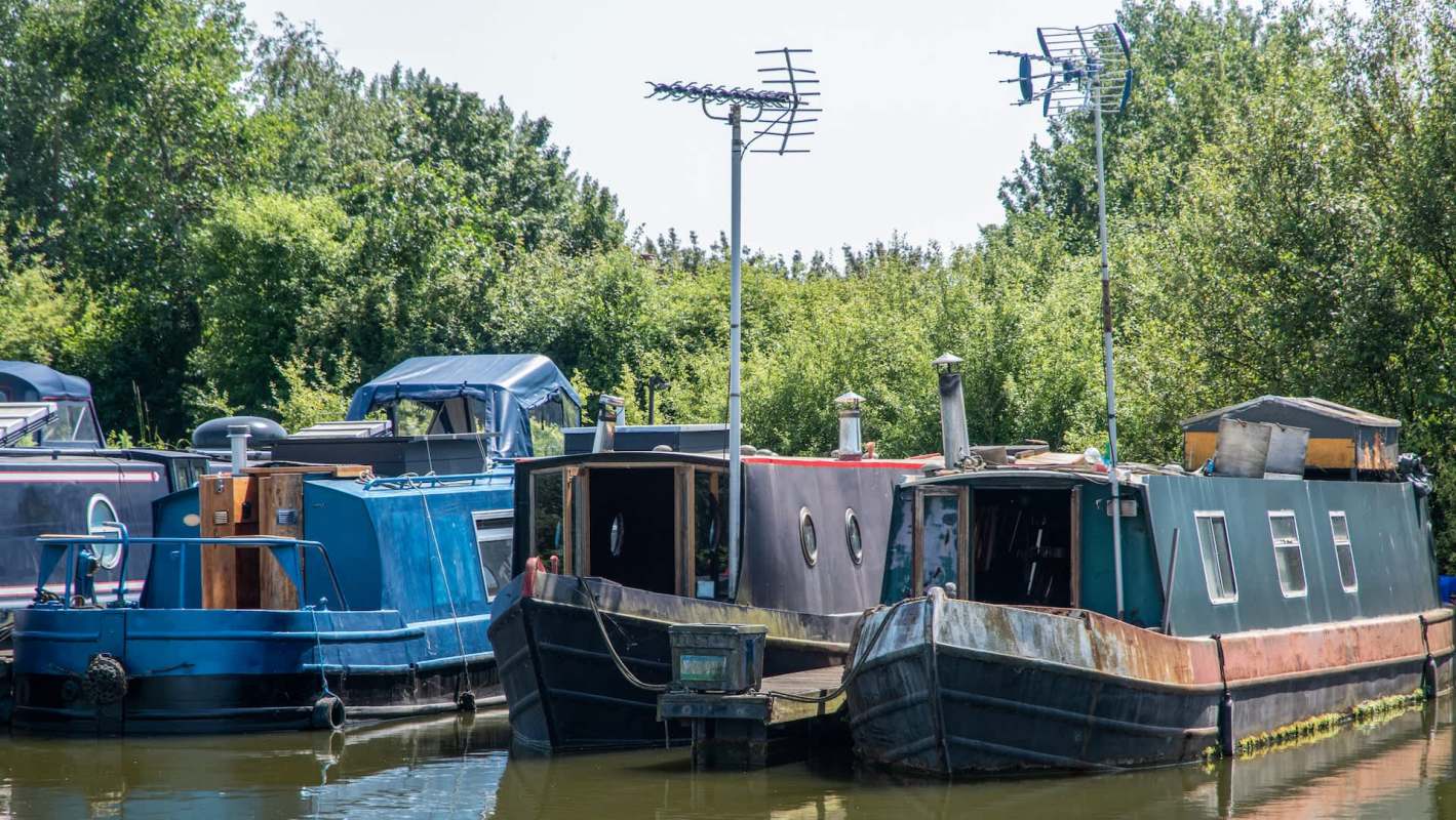 A group of houseboats moored on calm water surrounded by greenery.
