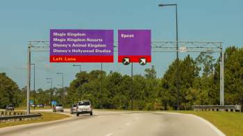A highway sign directing traffic to Magic Kingdom, Epcot, and other Disney destinations.