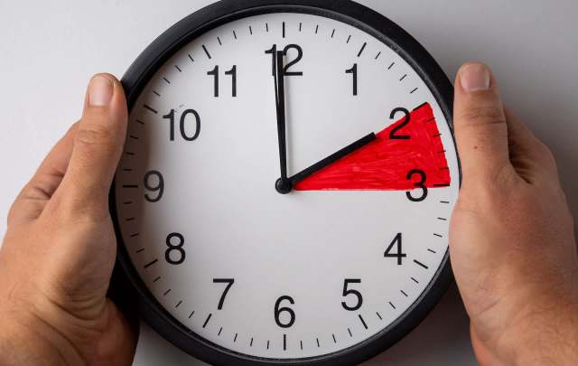 A person holding a clock.