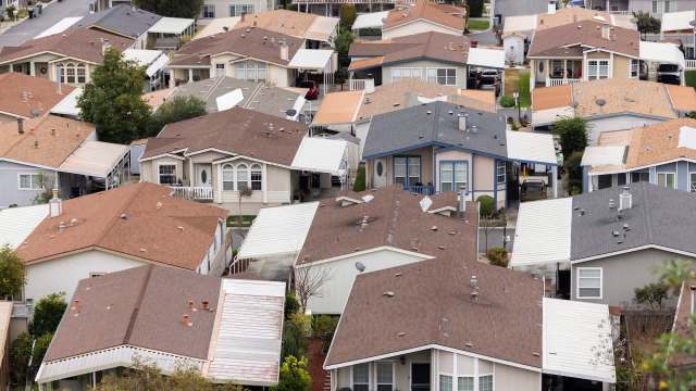 Aerial view of a residential mobile home park featuring multiple houses with varying roof colors and designs.
