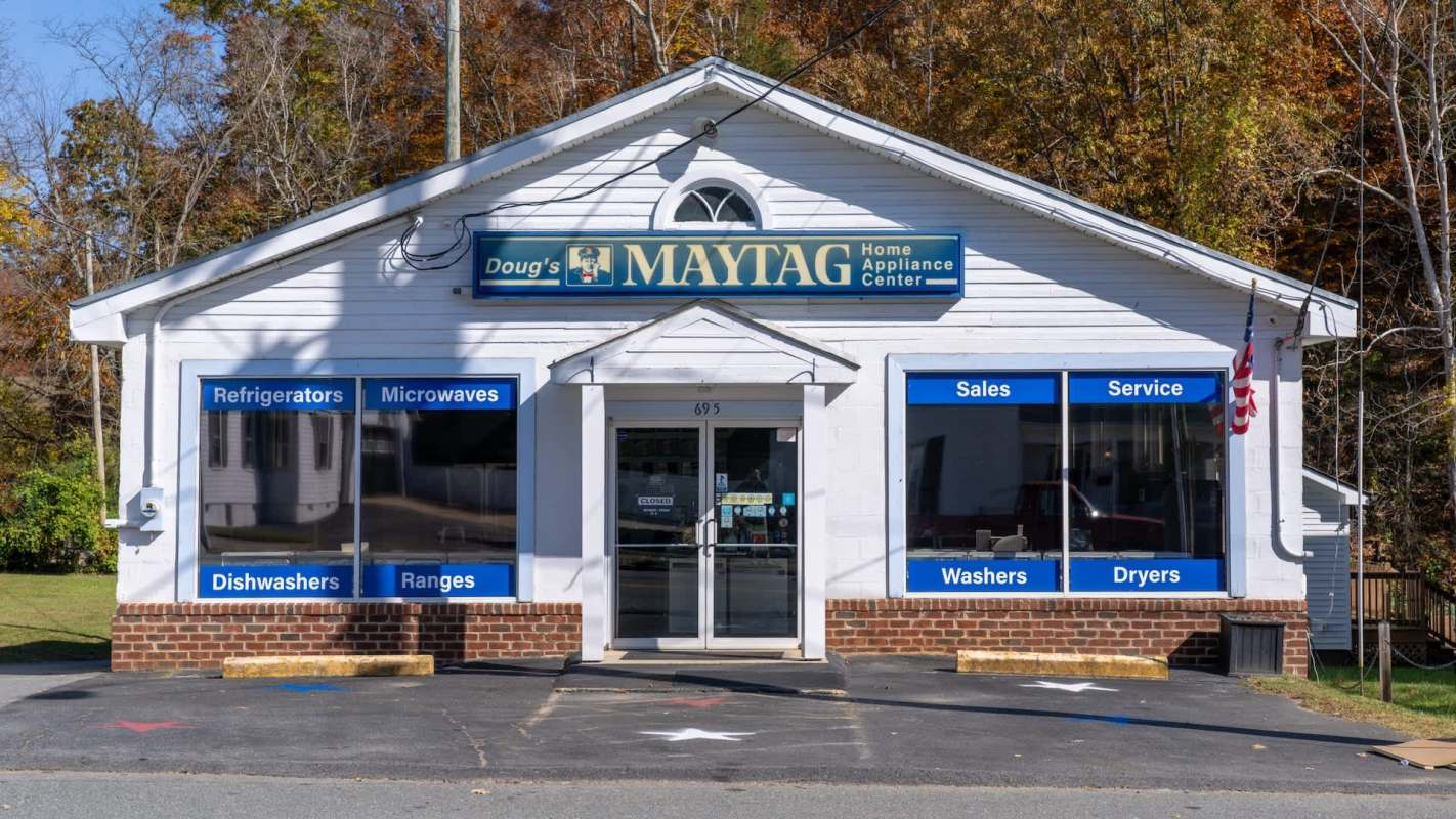 A home appliance store with window displays for refrigerators, microwaves, dishwashers, and other appliances.
