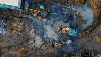 A construction site with machinery, dirt, and waterlogged areas.