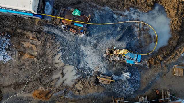 A construction site with machinery, dirt, and waterlogged areas.