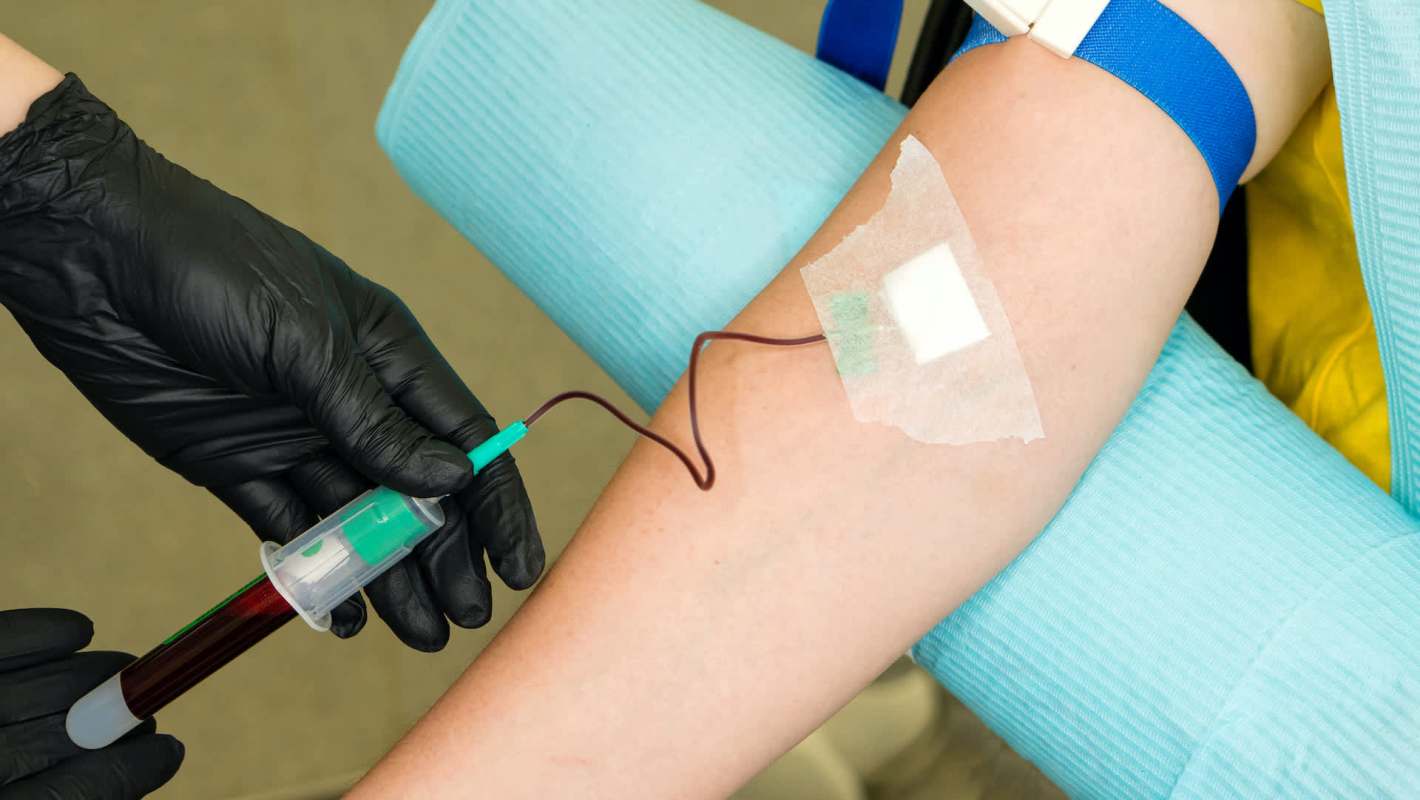 A healthcare worker drawing blood from a patient's arm.