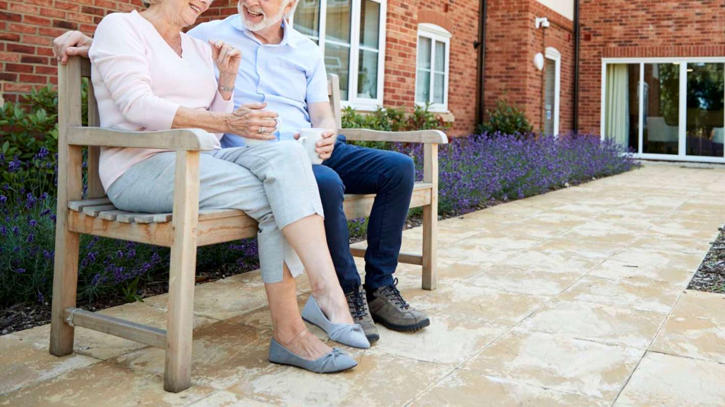 Two older people sitting on a bench.