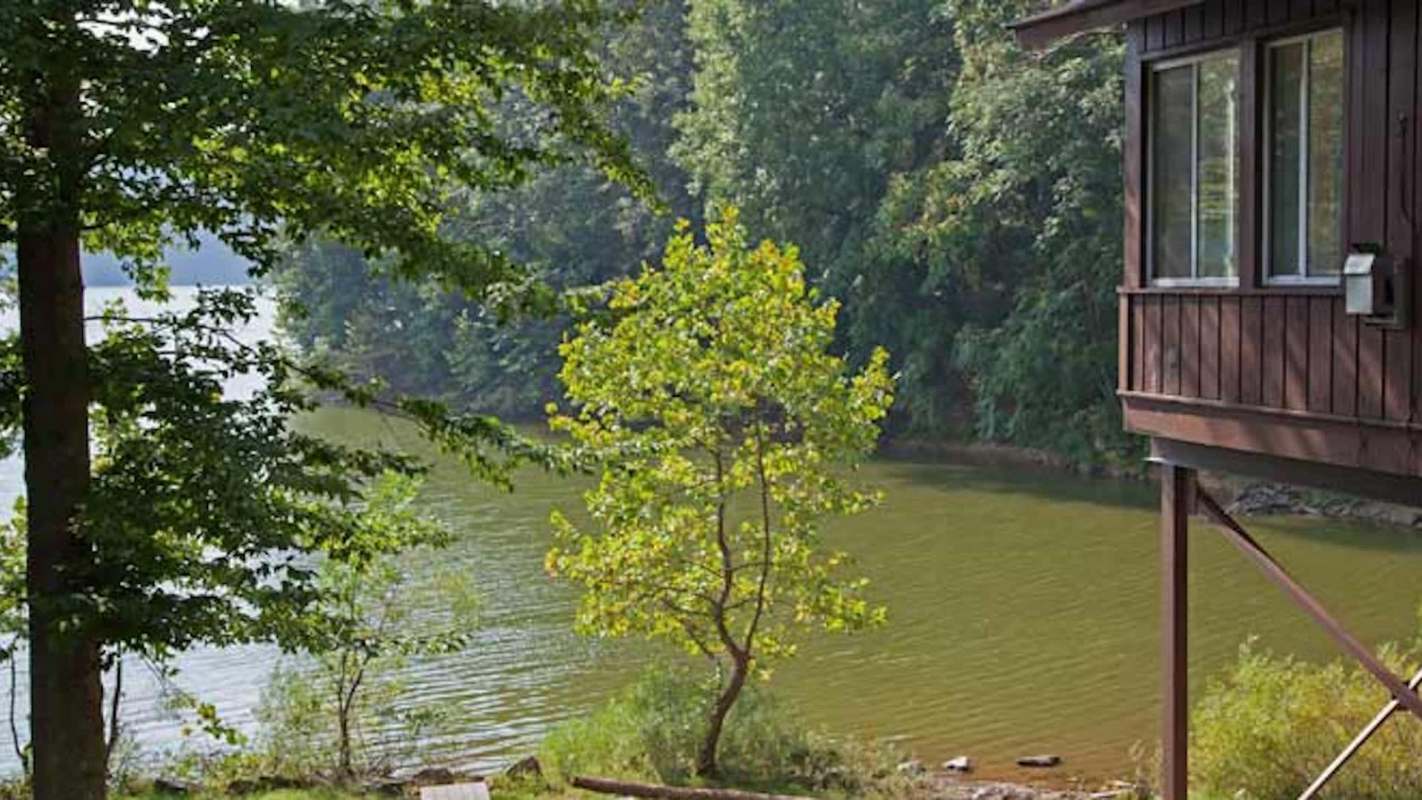 A wooden cabin overlooking a lake surrounded by trees.