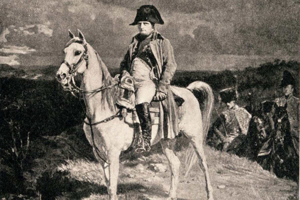 Napoleon, mounted in a coat and hat, with soldiers and horses in the background.