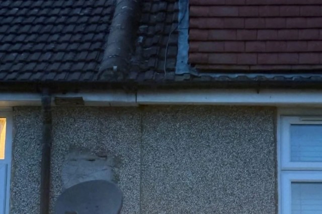 A satellite dish mounted to a wall between homes.
