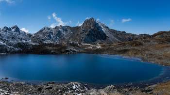 A tranquil blue lake surrounded by rocky mountains and a clear blue sky.