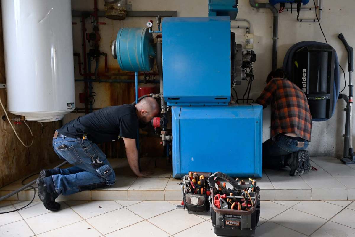 Two people work on a boiler.