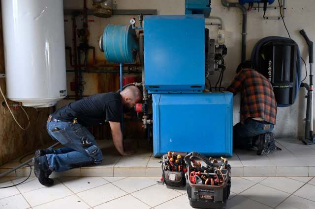 Two people work on a boiler.