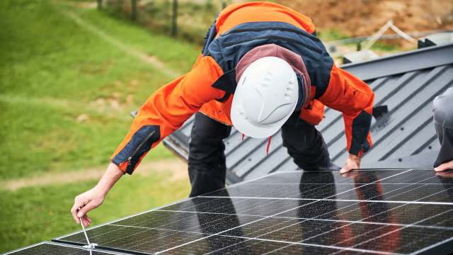 A person working on a solar panel installation on a roof.