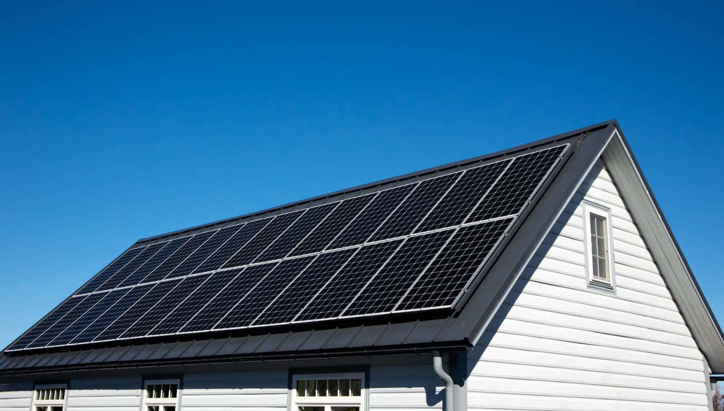 A house with solar panels installed on the roof against a clear blue sky.
