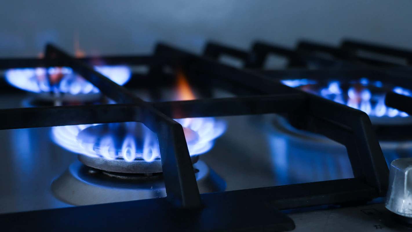 Gas burners ignited with blue flames on a stovetop.