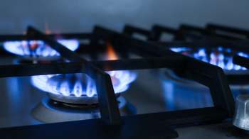 Gas burners ignited with blue flames on a stovetop.