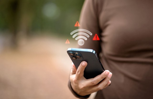 A person holds a smartphone displaying warning icons related to connectivity issues.