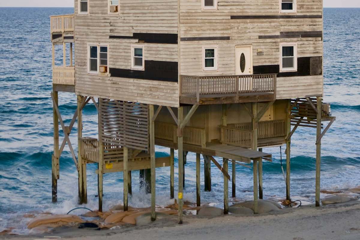 A house on stilts over ocean waves.