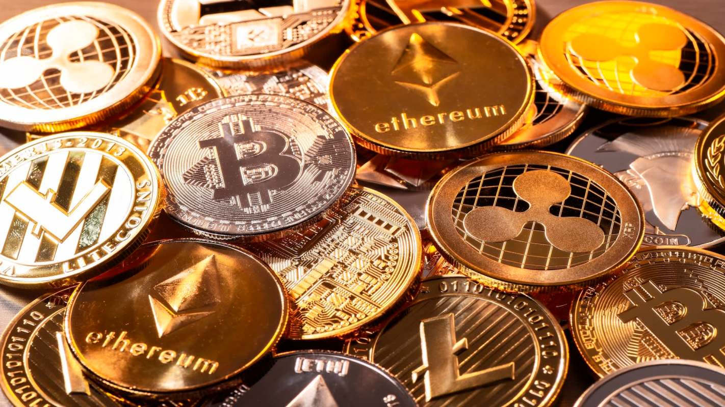 A collection of various cryptocurrency coins, including Bitcoin and Ethereum, scattered on a surface.