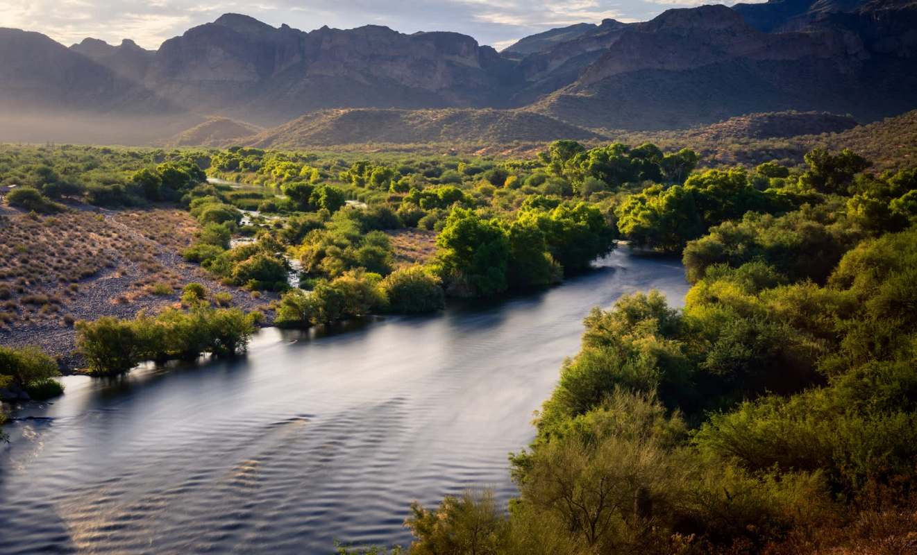 A river flows through a lush landscape with mountains in the background.