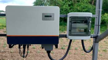 A solar inverter and electrical junction box mounted in a field.