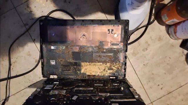 An open laptop displaying dust and debris on its internal components.