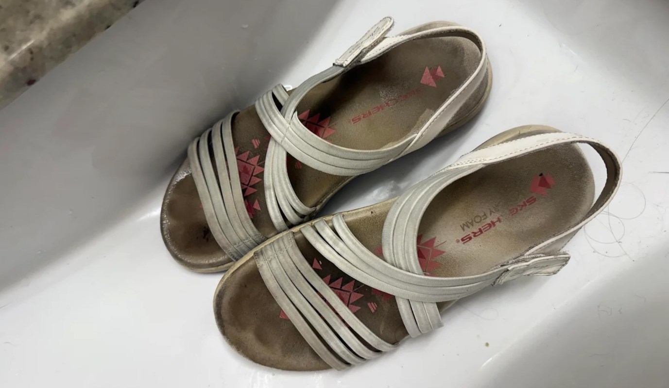 A pair of worn sandals resting on a white surface.