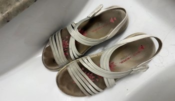 A pair of worn sandals resting on a white surface.