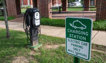 An electric vehicle charging station with a sign indicating designated parking for charging only.