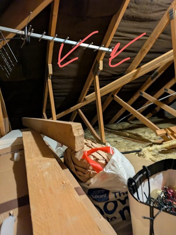 An attic with wooden trusses and arrows pointing to connection points.