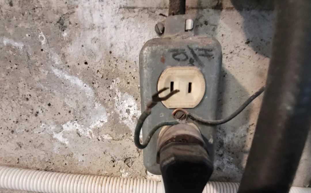 A pronged wire sticking out of an outlet.