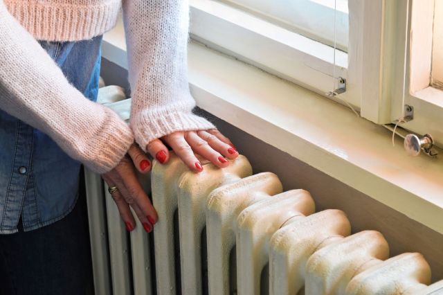 A woman with her hands on a radiator.