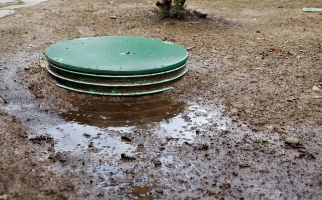 A green sewage tank in mud.