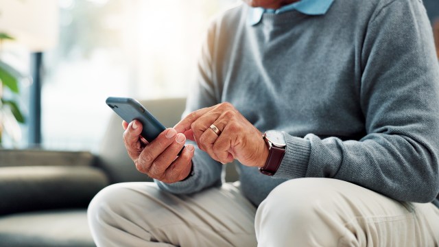 A person interacts with a smartphone while sitting on a couch.