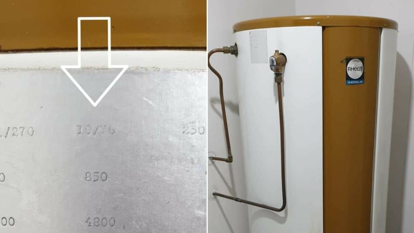 A water heater with a metal label showing specifications and a connection for pipes.
