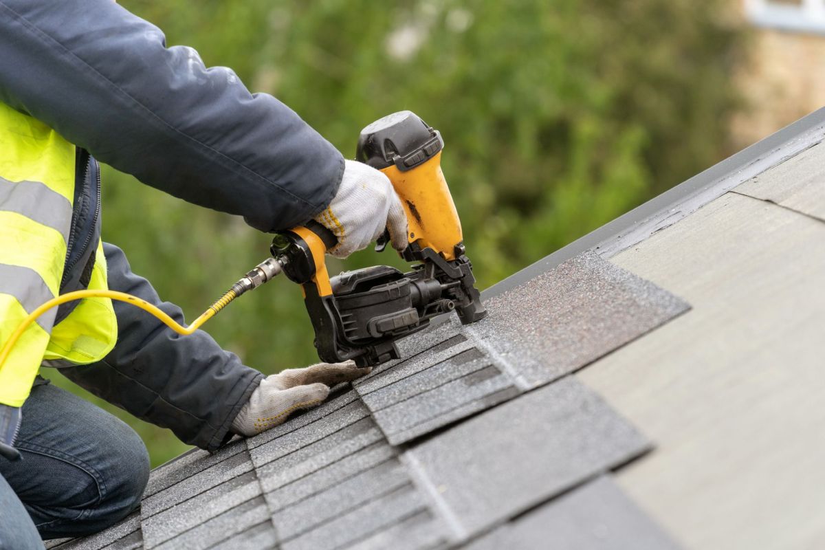 A worker installing new shingles on a roof.