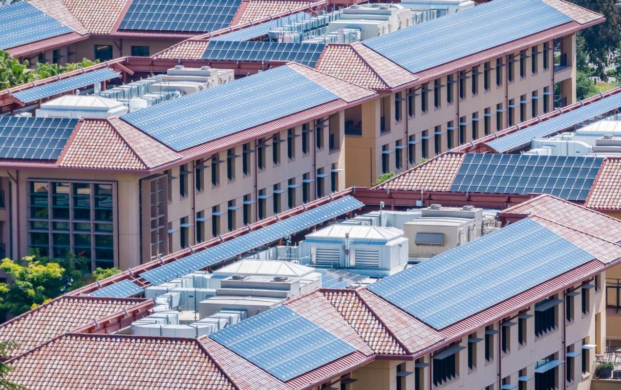 Rooftops with solar panels on buildings and air conditioning units.