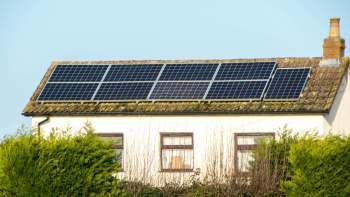Solar panels installed on the roof of a house surrounded by greenery.