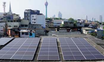 Solar panels installed on rooftops in Colombo, Sri Lanka, with the background featuring a telecommunications tower.