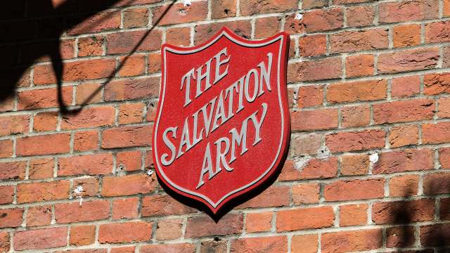 A red sign with "The Salvation Army" mounted on a brick wall.