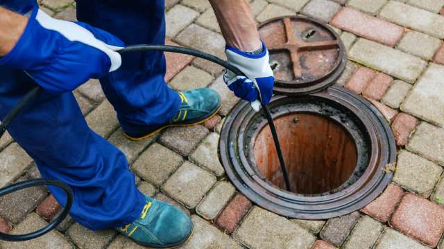A person using a sewer snake to clear a blocked drain.