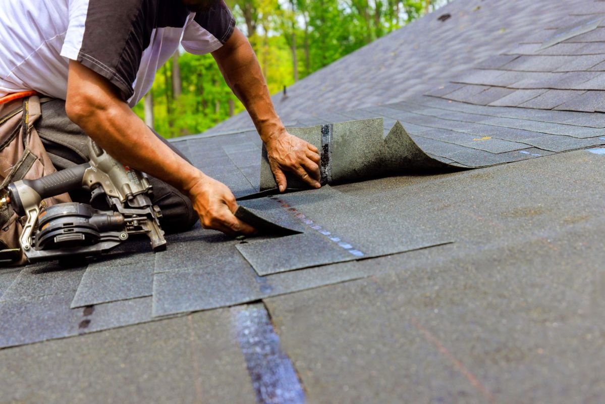 A worker putting down shingles.