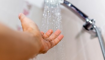 Water from a shower head flowing onto a hand.