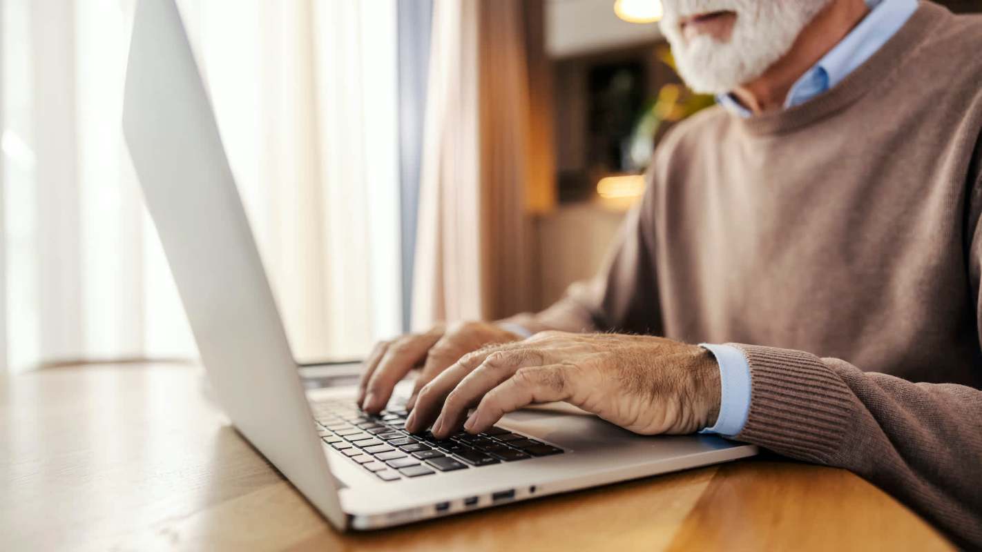An elderly person on a laptop.
