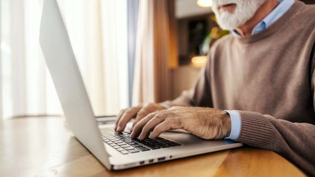 An elderly person on a laptop.