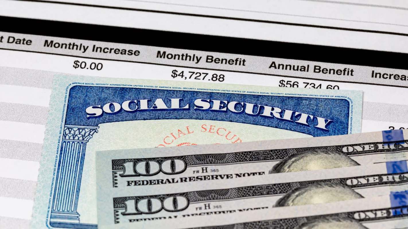 A Social Security card and three hundred dollar bills on a document showing benefit details.