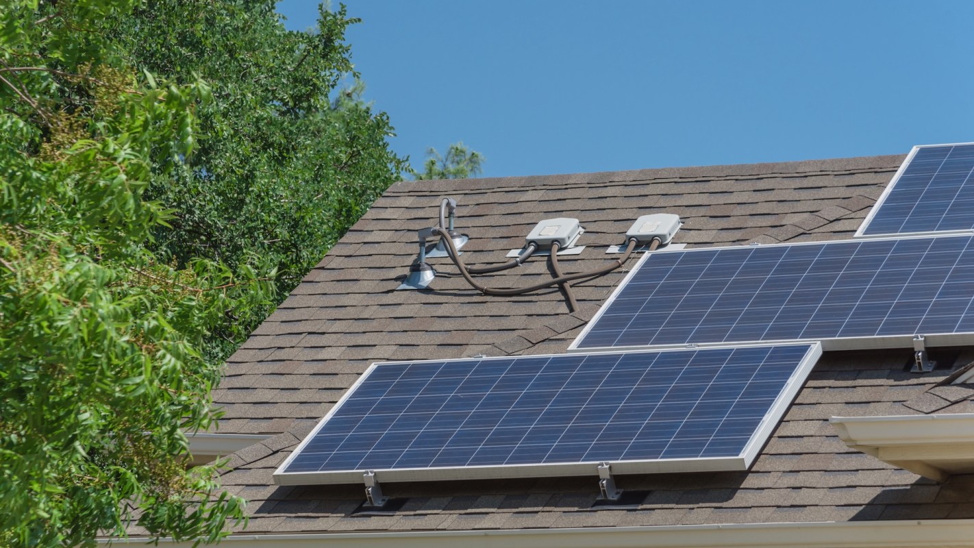 Solar panels installed on a roof with greenery in the background.