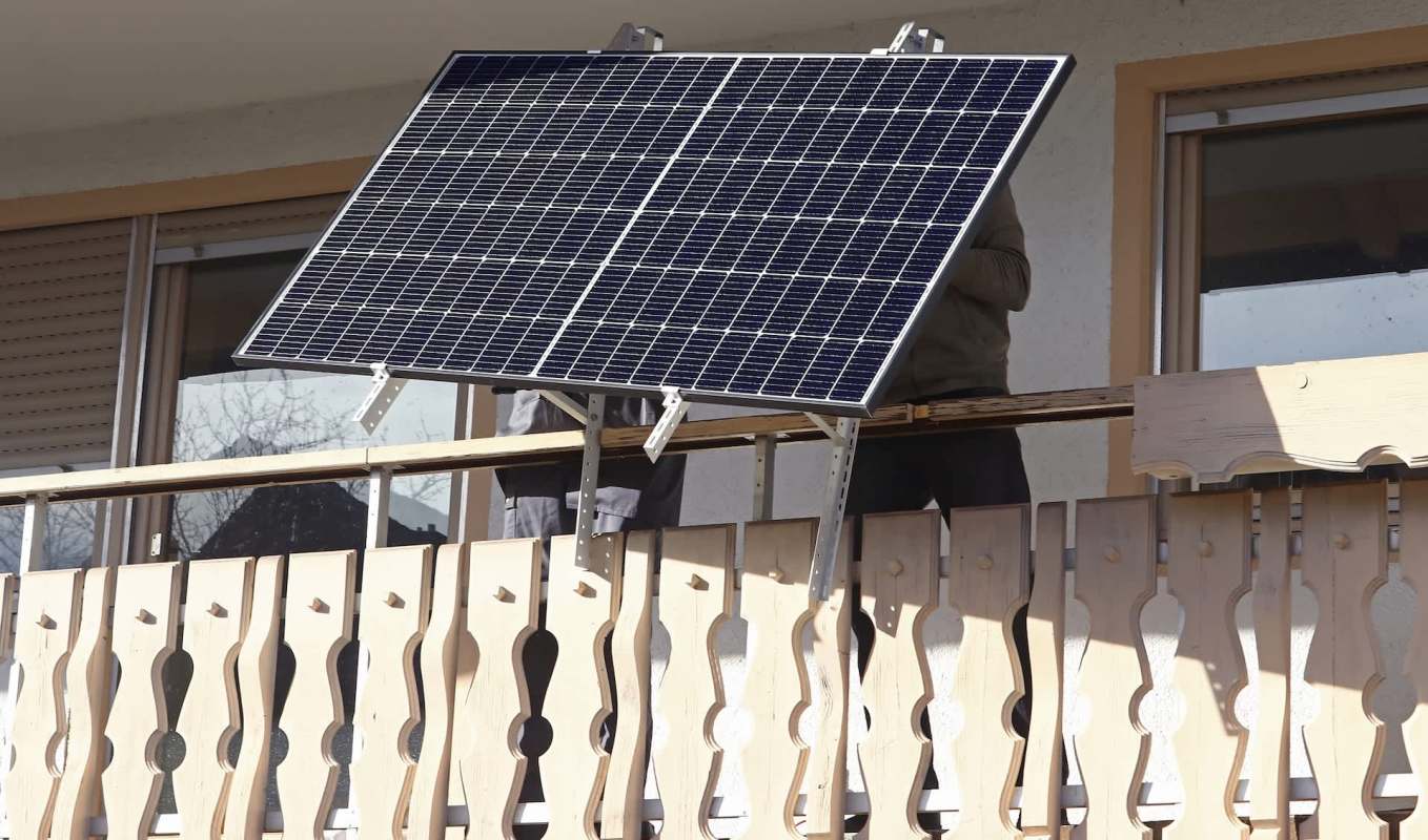 A solar panel is being installed on a wooden balcony.