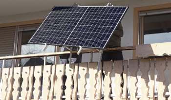 A solar panel is being installed on a wooden balcony.