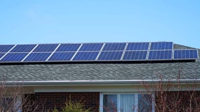 Solar panels installed on the roof of a house on a clear day.