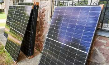 Several solar panels are leaning against a stone wall near a window.